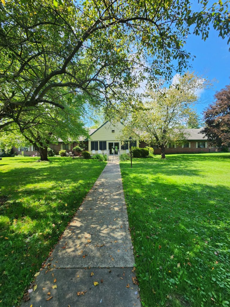 A nice building with a pathway leading up to it, surrounded by trees under a vibrant sky.